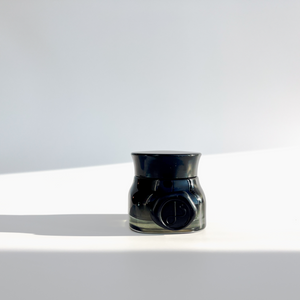 
                  
                    Green black jar on white background filled with skincare cream 
                  
                